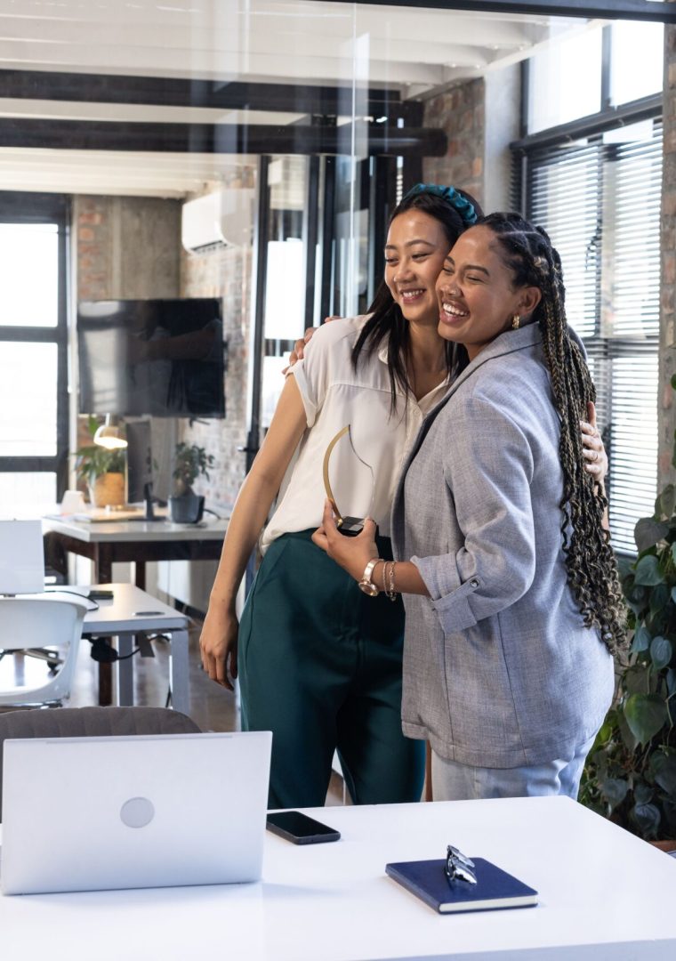 Colleagues hugging in modern office, celebrating success with joyful expressions. Teamwork, collaboration, celebration, corporate, friendship, happiness